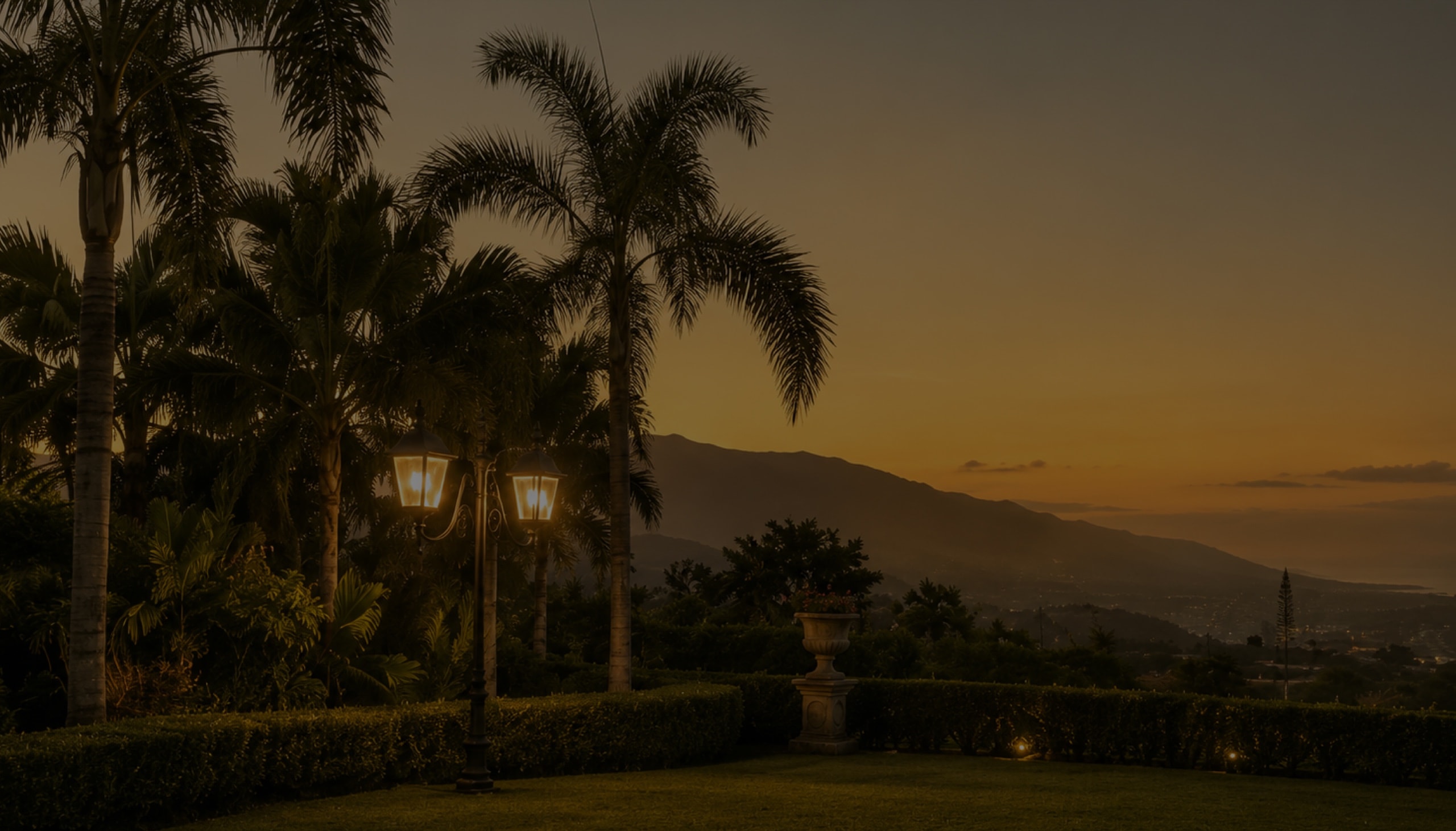 Hacienda gardens at sunset with palms and mountain views